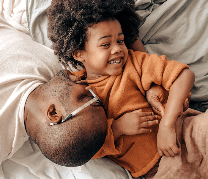 father and son on bed, both smiling